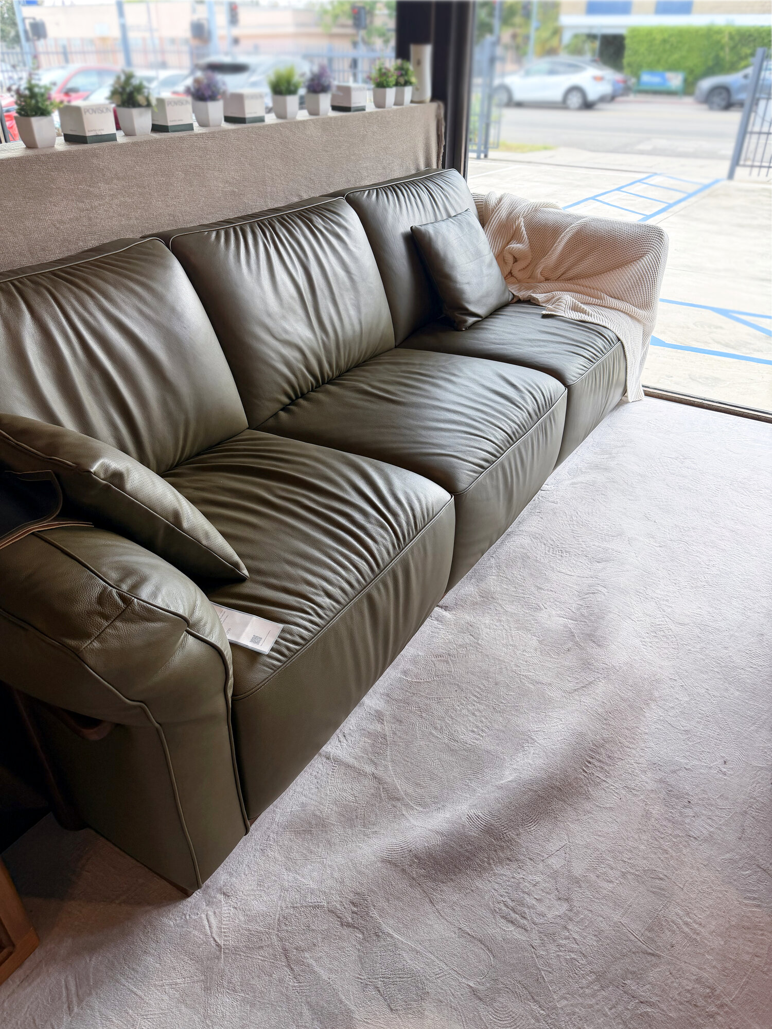 Side view of the Povison Cronus sofa in olive green leather at the showroom